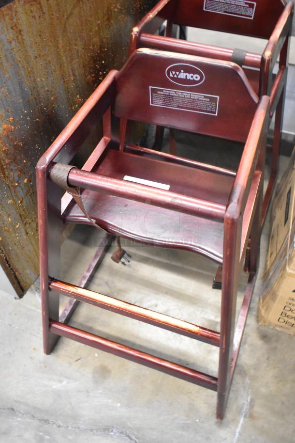 Two Winco wood pattern high chairs in used condition, featuring a rich brown finish and visible brand logo and safety labels.
