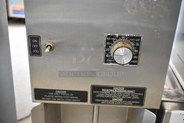 Duke stainless steel frozen drink mixer, 115V, with on/off/jog switch and timer. Caution labels visible.