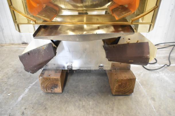 Stainless steel commercial countertop citrus juicer, 115 volts, 1 phase. Visible wear, resting on wooden blocks.