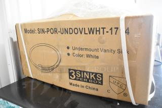 Boxed SIN-POR-UNDOVLWHT-1714 undermount vanity sink in white, labeled as new scratch and dent, three sinks per box.