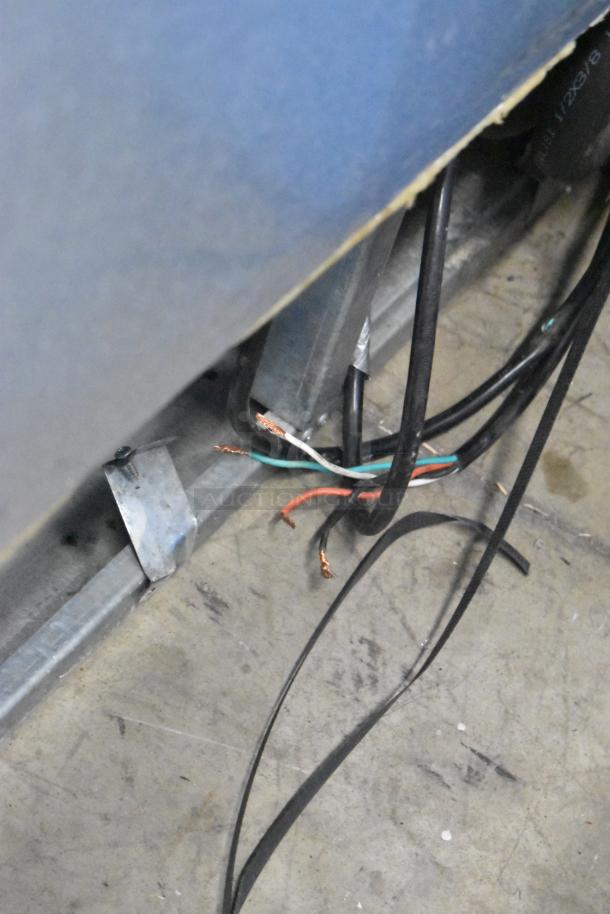Loose wiring on a Migali C-72FM commercial freezer, showing exposed wires and metal casing. Condition requires repair.