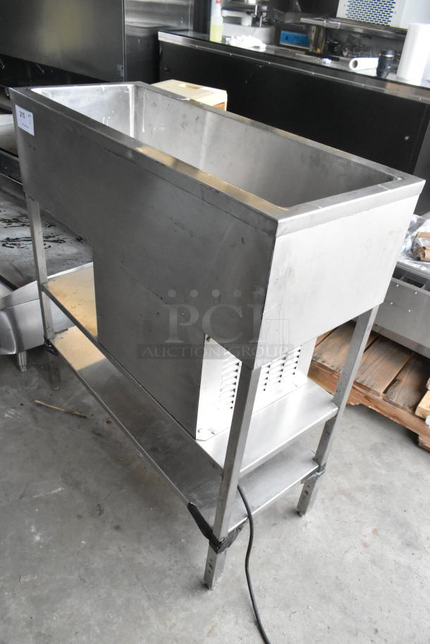 Stainless steel commercial refrigerated cold pan with open top, sturdy legs, and lower shelf; visible power cord attached.