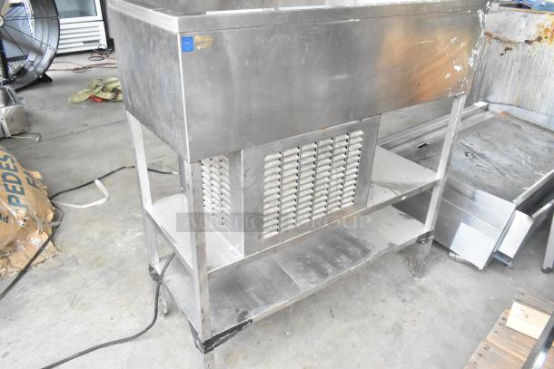 Stainless steel commercial refrigerated cold pan with open shelving, visible venting, and sturdy legs; shows some wear.