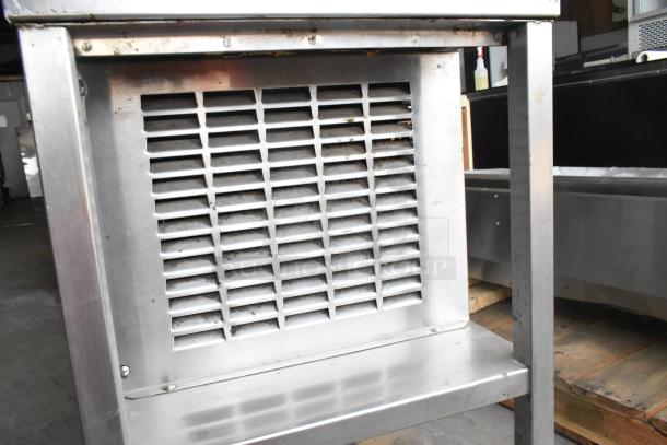 Stainless steel commercial refrigerated cold pan with ventilation grille, showing signs of wear. Ideal for food service.