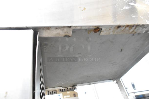 Stainless steel commercial refrigerated cold pan with visible wear and rust marks on the edges.
