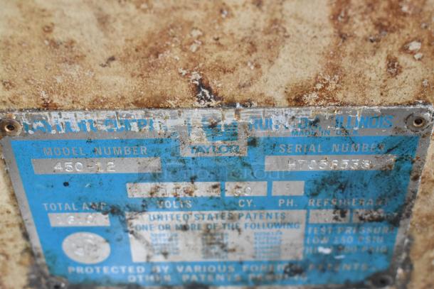 Taylor 450-12 beverage machine label, showing model, serial number H7056538, and 115V, 1-phase specs. Rust visible.