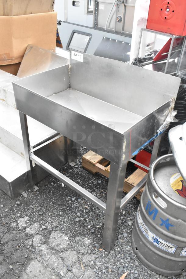 Metal Ice Bin Table with stainless steel construction, sturdy legs, and a spacious bin. Shows signs of wear, ideal for bars.