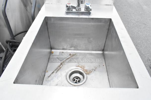 Stainless steel single bay sink with faucet and handles, visible wear and debris, suitable for kitchen or utility use.