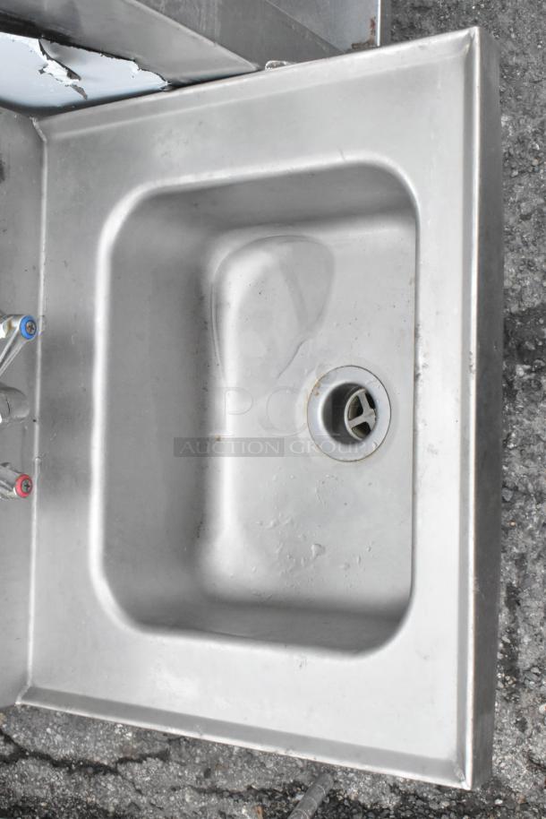 Stainless steel wall mount sink with faucet and handles, single bay, gently used condition, visible wear on corners.