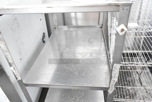 Metal 3-tier cart with commercial casters, showing moderate wear. Features sturdy metal shelves and handwritten markings on the frame.