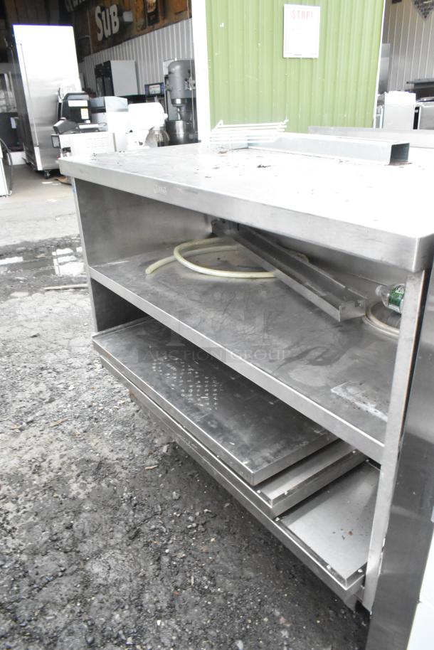 Stainless steel commercial table with 2 under shelves, on commercial casters, shows signs of wear.