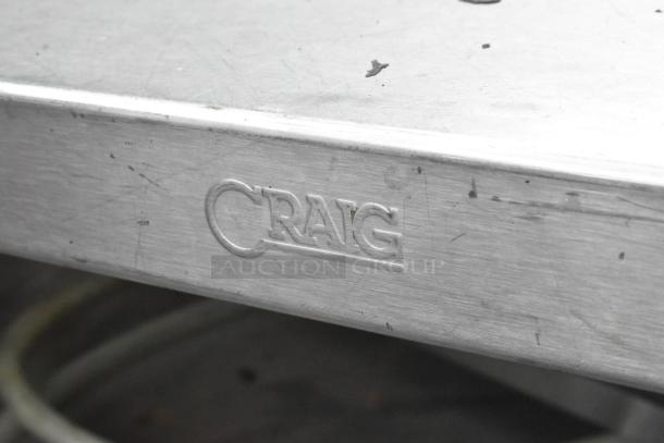 Stainless steel commercial table, features two under shelves and commercial casters. Engraved "CRAG" on side. Used condition.