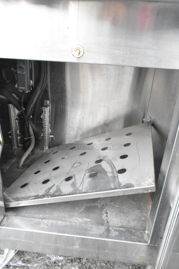 Stainless steel commercial undercounter cooler with visible interior details, showing wear and electrical components.
