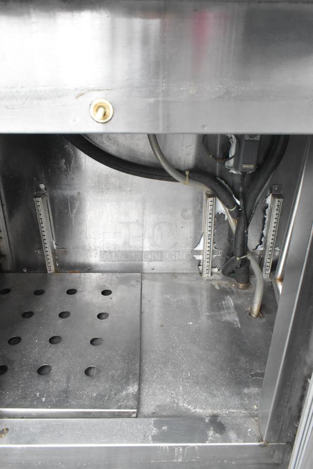 Stainless steel commercial undercounter cooler interior, showing two doors and drawers. Visible wear and wiring inside.