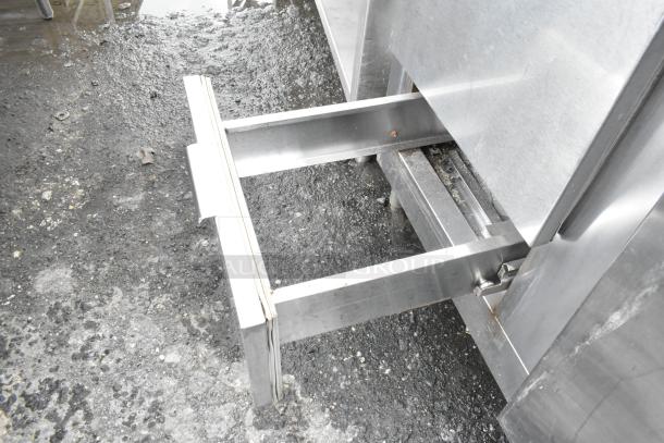 Stainless steel commercial undercounter cooler with open drawer, showing sturdy construction and minor wear.