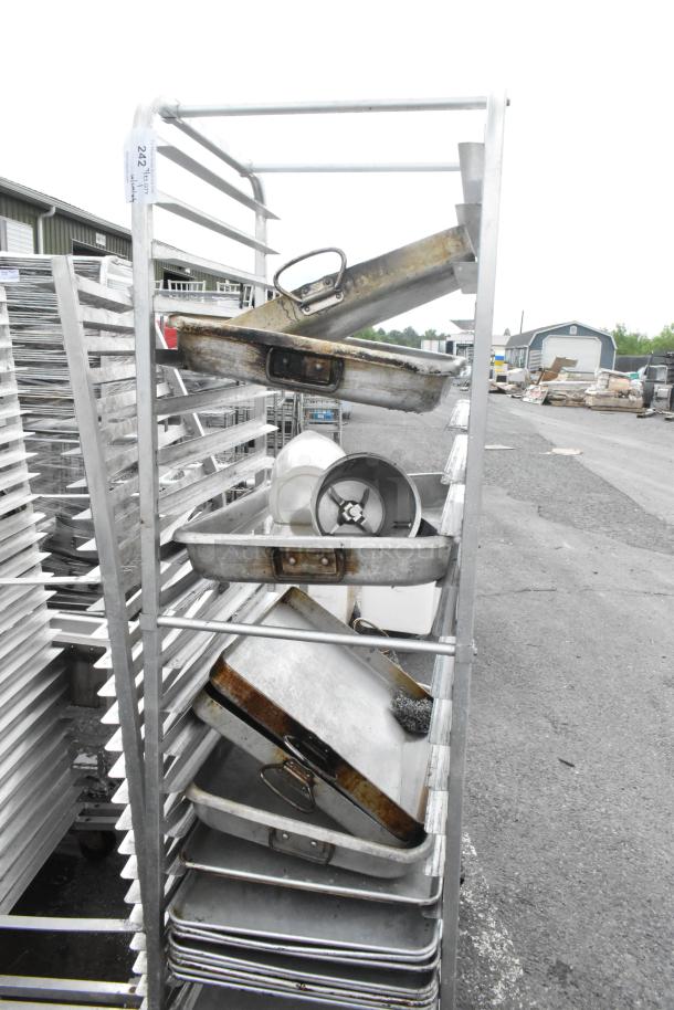 Metal commercial pan transport rack with 13 full-size baking pans and casters, used condition with visible wear.