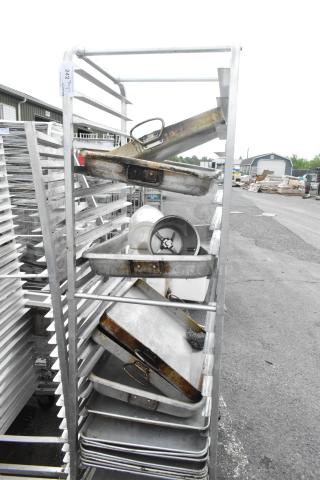 Metal commercial pan transport rack with 13 full-size baking pans and casters, used condition with visible wear.