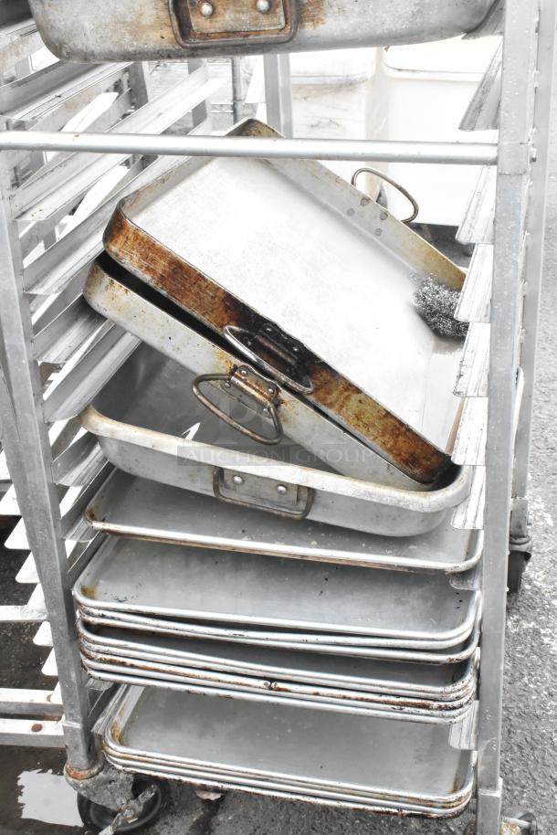Metal commercial pan transport rack on casters with 13 full-size metal baking pans, used condition.