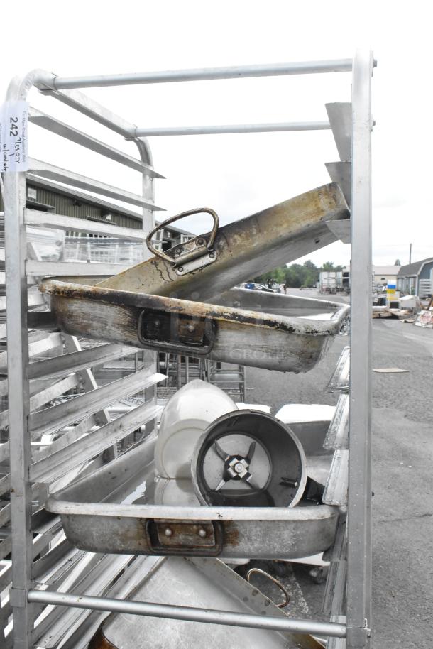 Metal commercial pan transport rack on casters with 13 full-size metal baking pans, shows signs of wear.