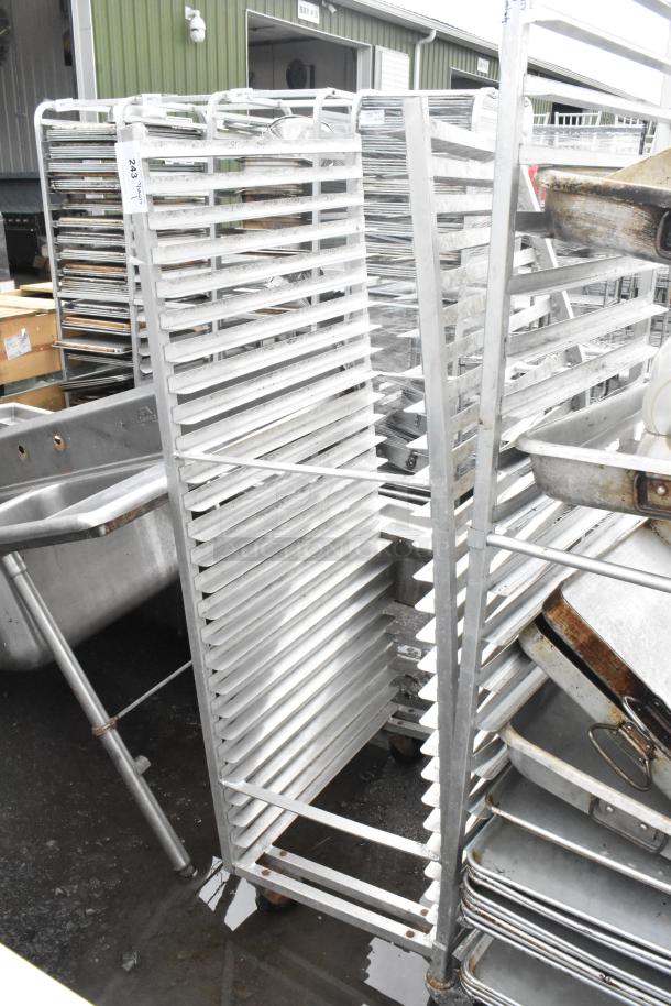 Metal commercial pan transport rack on casters, showing multiple shelves for storage, in used condition. Marked "243."