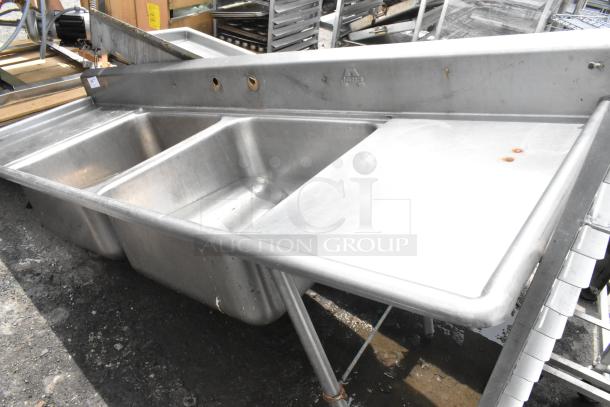 Stainless steel 2 bay sink with dual drain boards, no legs, slightly worn, visible rust spots, NSF logo on backsplash.
