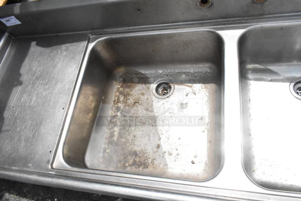 Stainless Steel 2 Bay Sink with Dual Drain Boards, no legs, some rust and wear visible, suitable for commercial use.