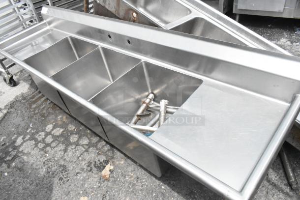 Stainless steel 3 bay sink with dual drain boards, durable construction, few visible fixtures, ideal for commercial use.