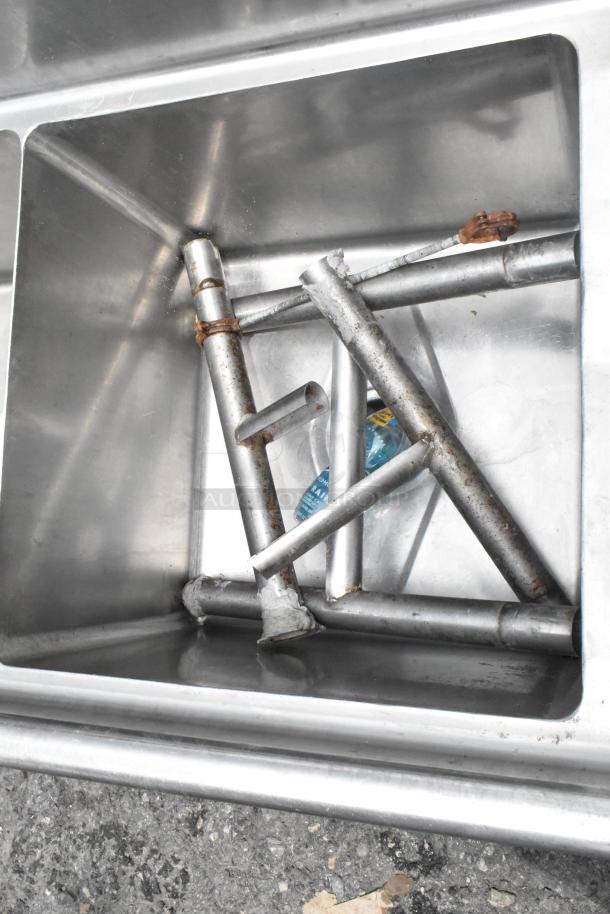 Stainless steel 3 bay sink with dual drain boards, showing moderate wear and rust on the metal frames.