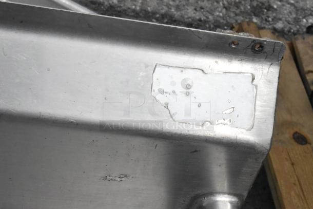 Stainless steel 3 bay sink with dual drain boards, showing corner detail. Some wear visible. Ideal for commercial use.