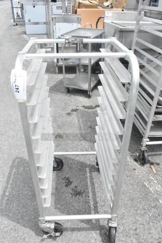 Commercial metal pan transport rack on casters, multiple shelves, used condition, auction tag "247" visible.
