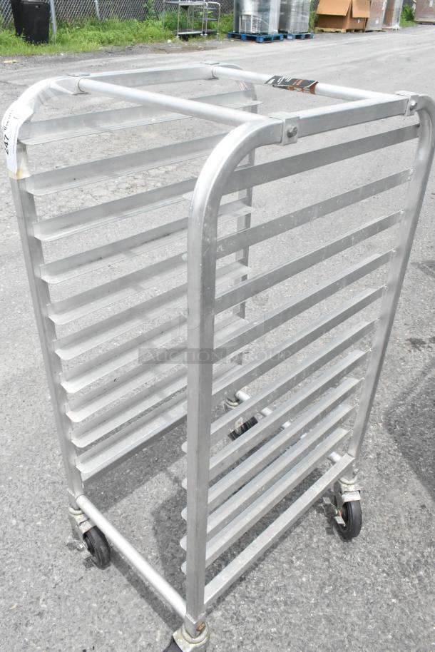 Metal pan transport rack with 11 shelves, commercial casters, and sturdy frame. Used condition. Tag number visible.