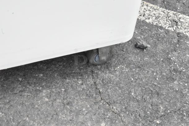 2 white poly ingredient bins with commercial casters, shown on pavement. Durable bins for efficient kitchen storage.