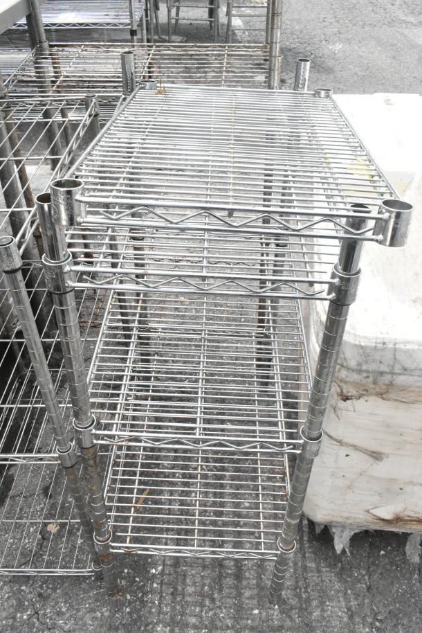 Two chrome finish, three-tier wire shelving units measuring 24x14x34 inches, in used condition.