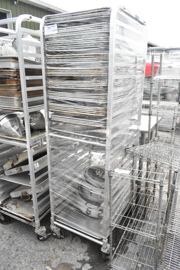 Metal pan transport rack on commercial casters, wrapped in plastic, containing 46 full-size baking pans, used condition.
