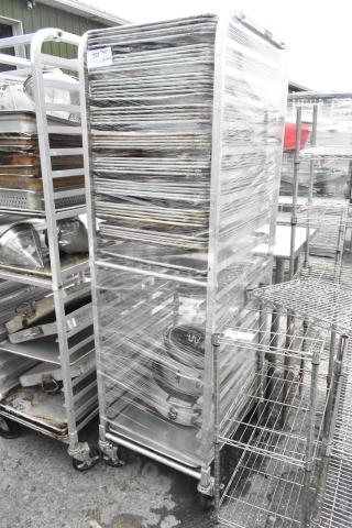 Metal pan transport rack on commercial casters, wrapped in plastic, containing 46 full-size baking pans, used condition.