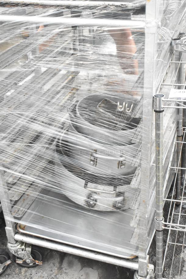 Metal pan transport rack with commercial casters, wrapped, containing 46 metal full-size baking pans.
