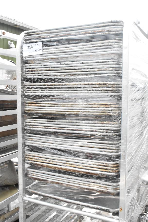 Metal pan transport rack on commercial casters with 46 full-size baking pans, wrapped and labeled with item details.