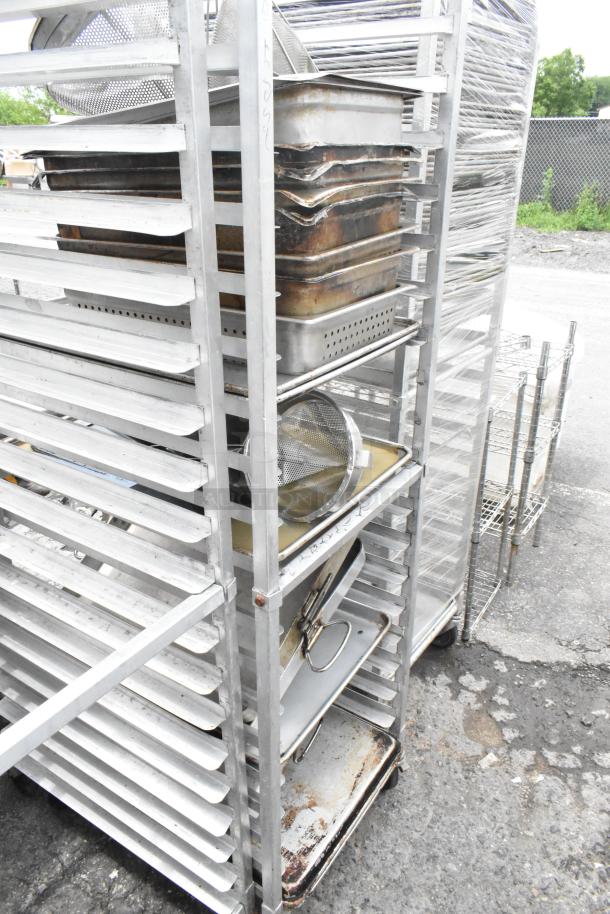 Metal pan transport rack on casters with 7 full-size baking pans and 8 drop-in bins, showing moderate wear.