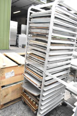 Metal pan transport rack on commercial casters with 40 full-size baking and muffin pans, visible wear, used condition.