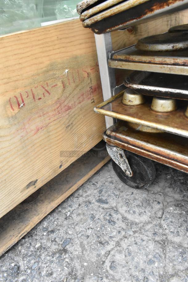 Metal pan transport rack on commercial casters, holding 40 full-size baking pans including muffin pans. Used condition.
