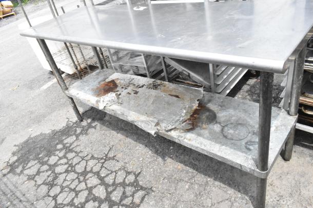 Stainless steel table with a metal under shelf, showing signs of rust and wear. Ideal for industrial or kitchen use.