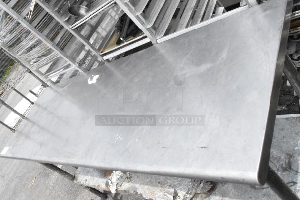 Stainless steel table with metal under shelf, minor surface wear, ideal for industrial or kitchen use.