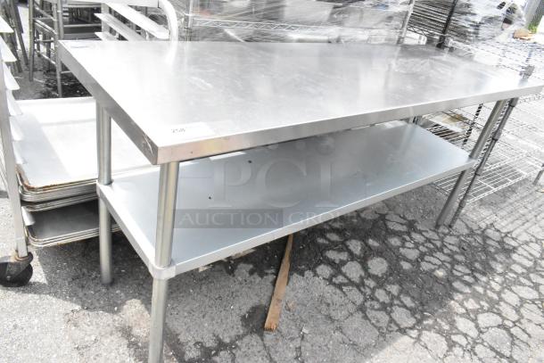 Stainless steel table with metal under shelf, featuring sturdy legs and a smooth surface. Appears in good condition.