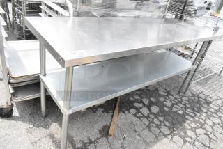 Stainless steel table with metal under shelf, featuring sturdy legs and a smooth surface. Appears in good condition.