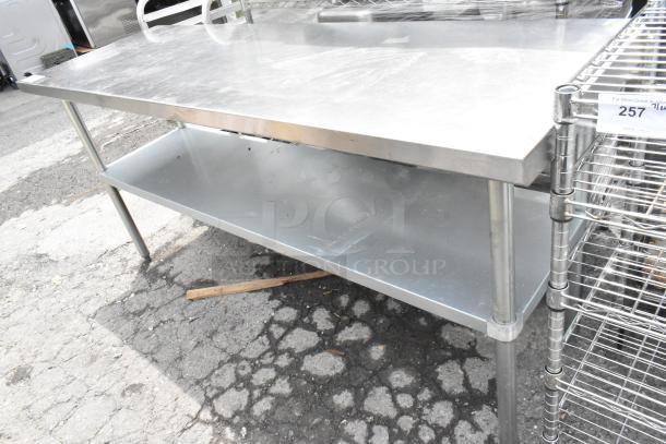 Stainless steel table with metal under shelf, in used condition, featuring sturdy legs and spacious work surface.