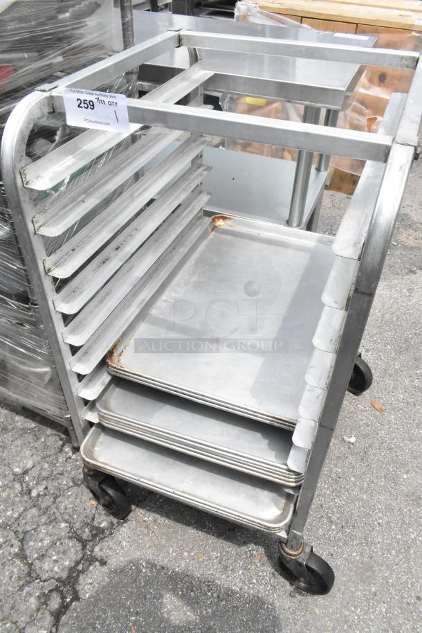 Metal pan transport rack on commercial casters with 11 metal baking pans. Some rust present. Auction tag visible.