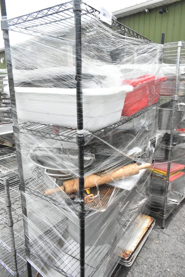Black 4-tier wire shelving unit with contents including utensils, rolling pin, and metal baking pans, shrink-wrapped for auction.