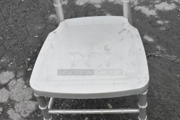 Silver Chiavari stackable banquet chair, used condition, with visible scuffs on seat. Sturdy design, ideal for events.