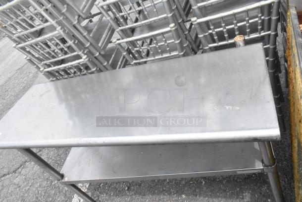 Stainless steel table with metal under shelf, industrial design, showing minimal wear, ideal for kitchen or workspace use.