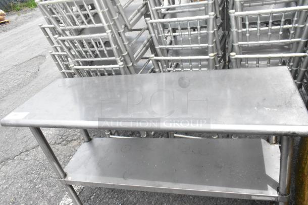 Stainless steel table with a metal under shelf. Shows signs of wear. Ideal for commercial kitchen use.